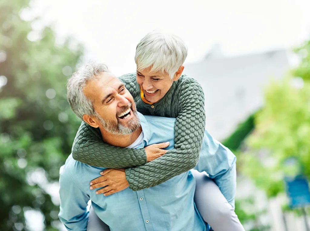 happy older couple, man and wife, laughing and. enjoying spending time together on a sunny day in the park